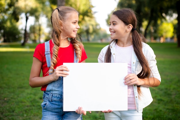 Dos muchachas felices que sostienen un papel en sus manos