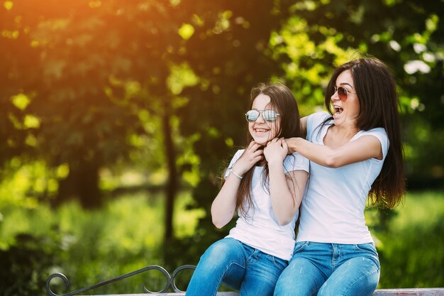 Dos muchachas que se divierten el sentarse en parque