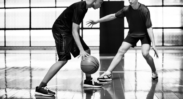 Foto gratuita dos muchachos adolescentes jugando baloncesto juntos en la cancha