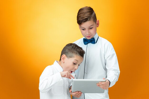 Los dos muchachos usando laptop en espacio naranja