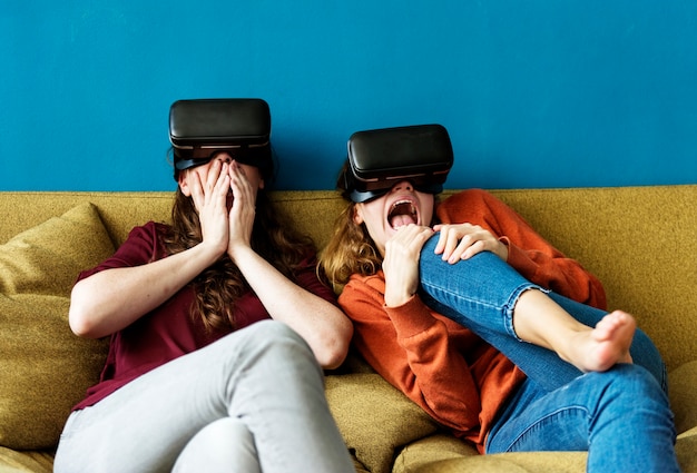 Dos mujer caucásica utilizando VR en un sofá