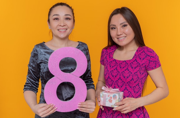 Dos mujeres asiáticas felices celebrando el día internacional de la mujer con el número ocho