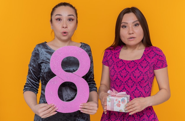 Dos mujeres asiáticas felices y sorprendidas celebrando el día internacional de la mujer con el número ocho