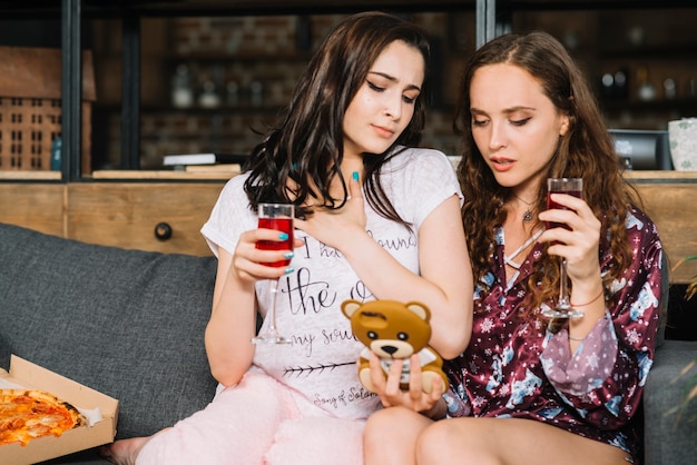 Dos mujeres con bebidas mirando el teléfono celular