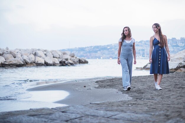 Dos mujeres caminando en la playa de arena