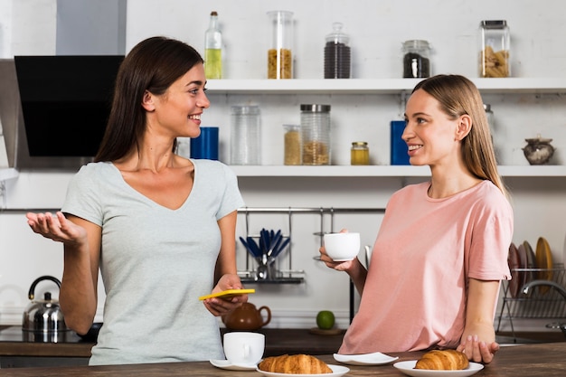 Dos mujeres en casa charlando con una taza de café
