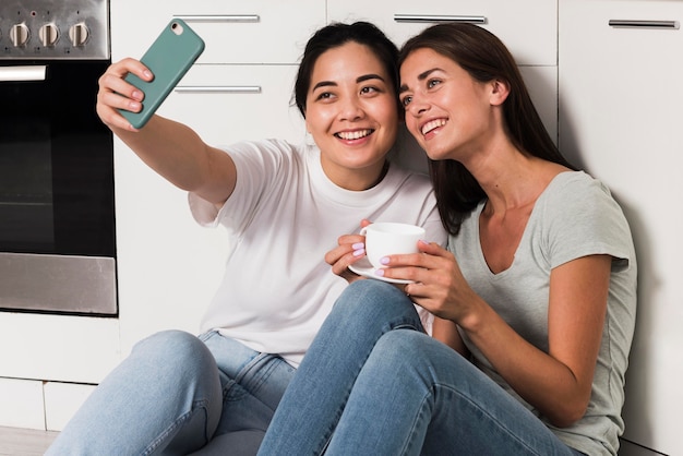 Dos mujeres en casa en la cocina tomando un selfie