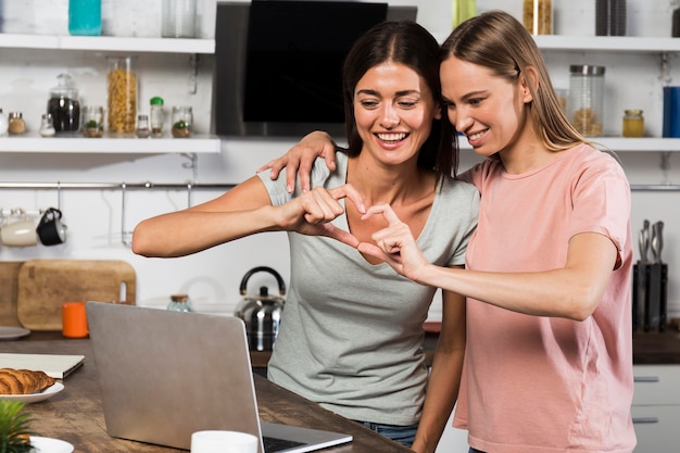 Dos mujeres en casa mostrando el corazón durante el video chat