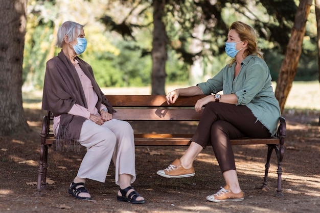 Dos mujeres conversando con máscaras médicas al aire libre en un hogar de ancianos