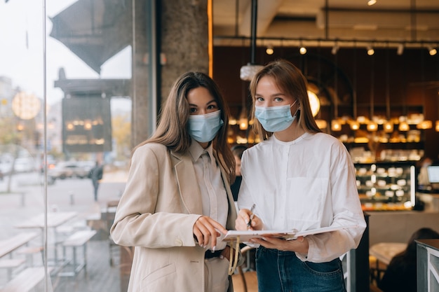 Foto gratuita dos mujeres empresarias con sus máscaras faciales debatiendo diferentes puntos de vista sobre el trabajo