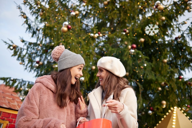 Foto gratuita dos mujeres y un enorme árbol de navidad.