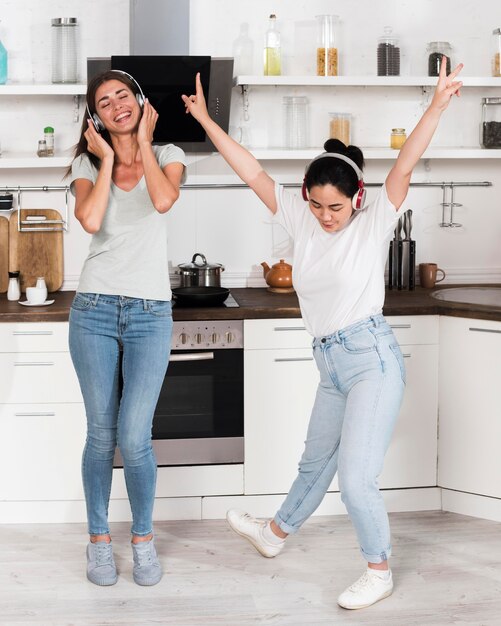 Dos mujeres escuchando y bailando música con auriculares