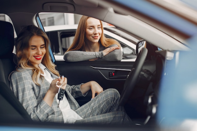 Dos mujeres con estilo en un salón de autos