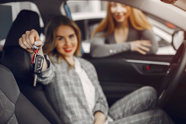 Dos mujeres con estilo en un salón de autos