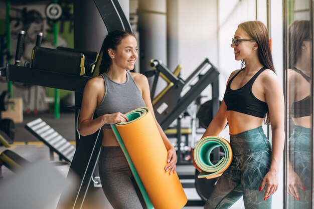 Dos mujeres en el gimnasio con colchoneta de yoga