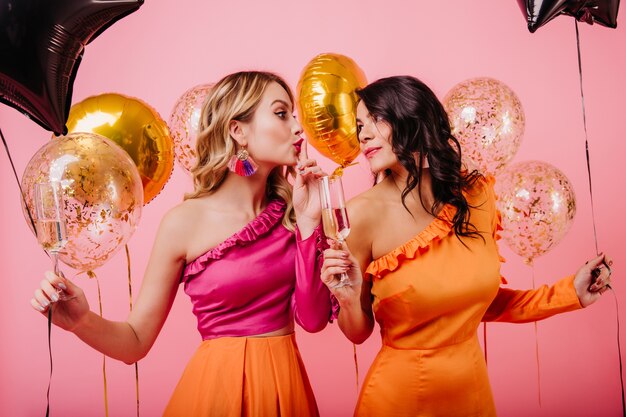 Dos mujeres con globos brillantes hablando en fiesta