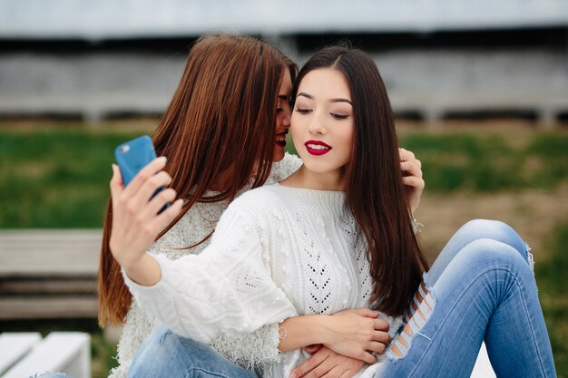 Dos mujeres haciendo selfie en el banco del parque
