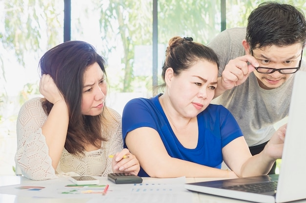 Dos mujeres y un hombre están trabajando seriamente juntos en la oficina moderna.