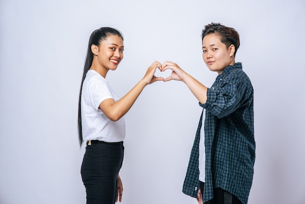 Dos mujeres jóvenes se aman en forma de corazón de marca de mano.