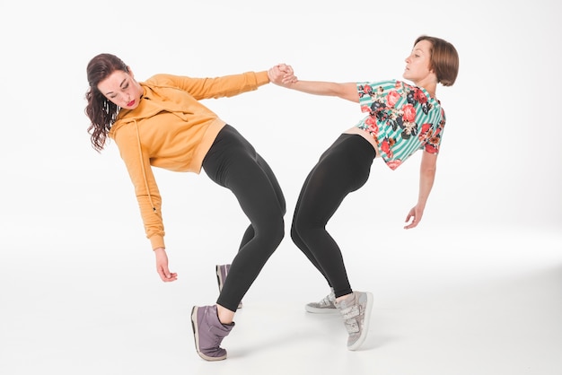 Foto gratuita dos mujeres jóvenes bailando contra el fondo blanco