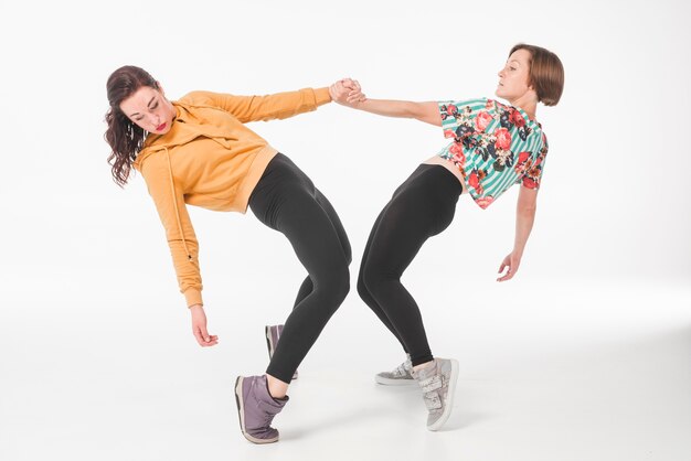 Dos mujeres jóvenes bailando contra el fondo blanco