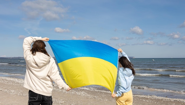 Dos mujeres jóvenes con la bandera de ucrania en el fondo del mar