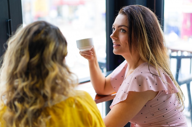 Dos mujeres jóvenes bebiendo café en la cafetería