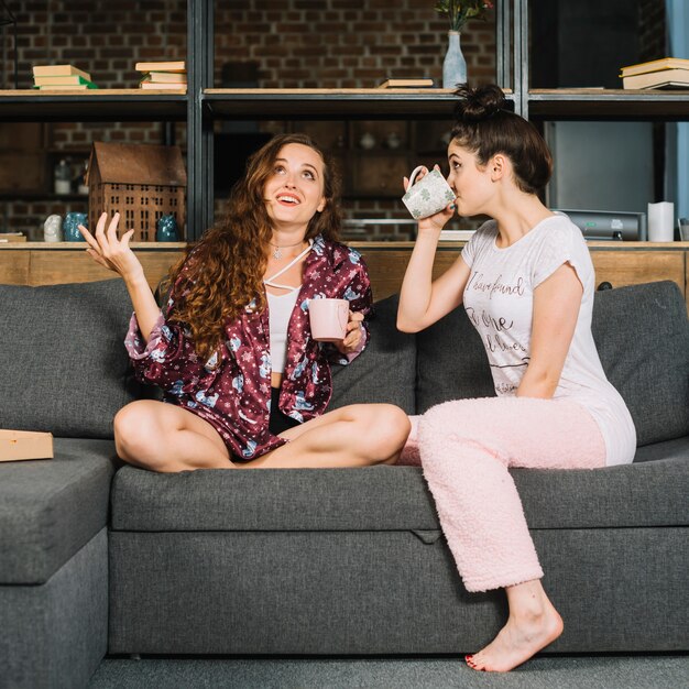 Dos mujeres jóvenes bebiendo café en casa