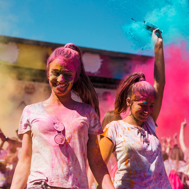 Dos mujeres jóvenes cubiertas con holi bailando en el festival holi.