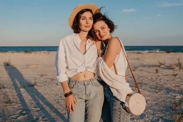 Dos mujeres jóvenes divirtiéndose en la playa al atardecer, romance de amor lesbiana gay