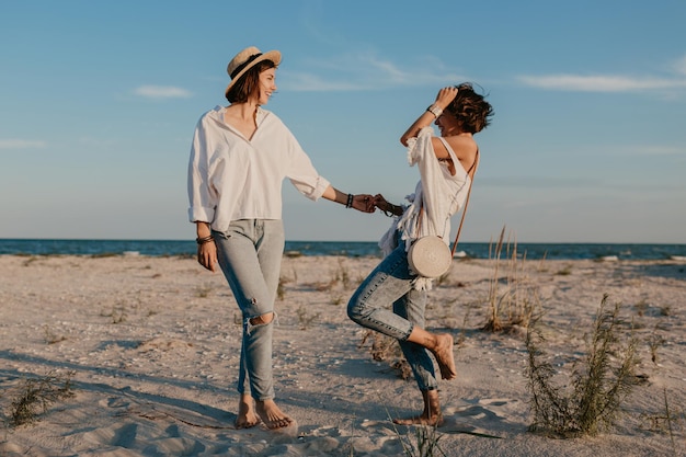 Dos mujeres jóvenes divirtiéndose en la playa al atardecer.