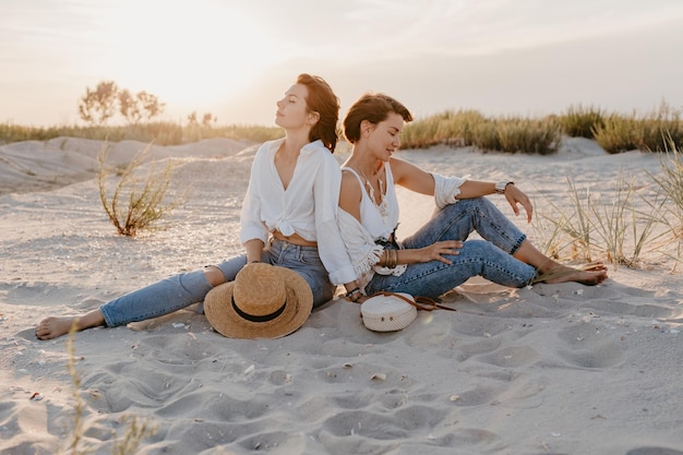 Dos mujeres jóvenes divirtiéndose en la playa al atardecer.