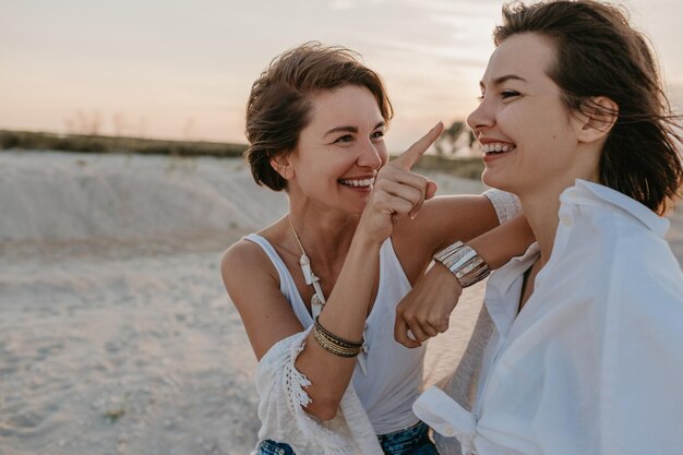 Dos mujeres jóvenes divirtiéndose en la playa al atardecer.