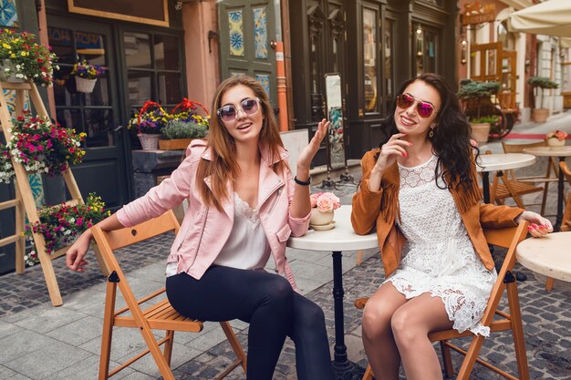 Dos mujeres jóvenes con estilo sentado en el café