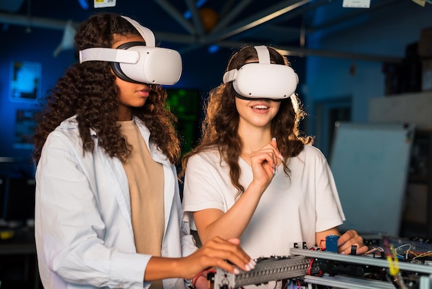 Foto gratuita dos mujeres jóvenes con gafas vr haciendo experimentos en robótica en un laboratorio robot sobre la mesa