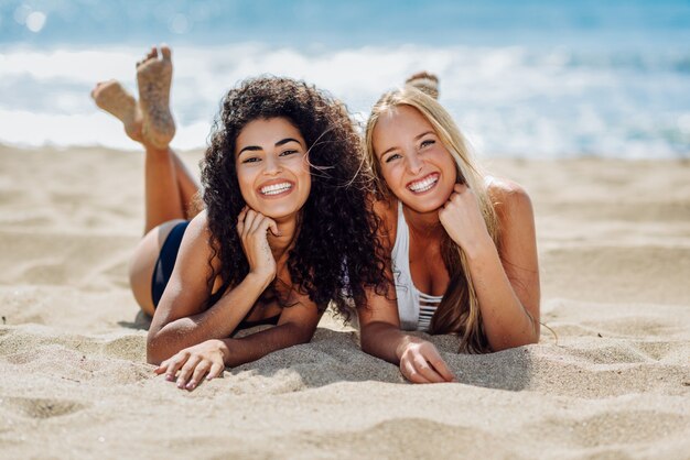 Dos mujeres jóvenes con hermosos cuerpos en trajes de baño en una playa tropical.
