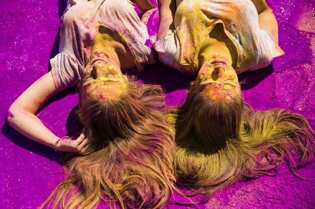 Dos mujeres jóvenes en polvo de color holi púrpura