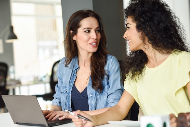 Foto gratuita dos mujeres jóvenes que estudian con una computadora portátil.