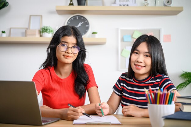 Dos mujeres jóvenes que trabajan con ordenadores portátiles sobre la mesa.