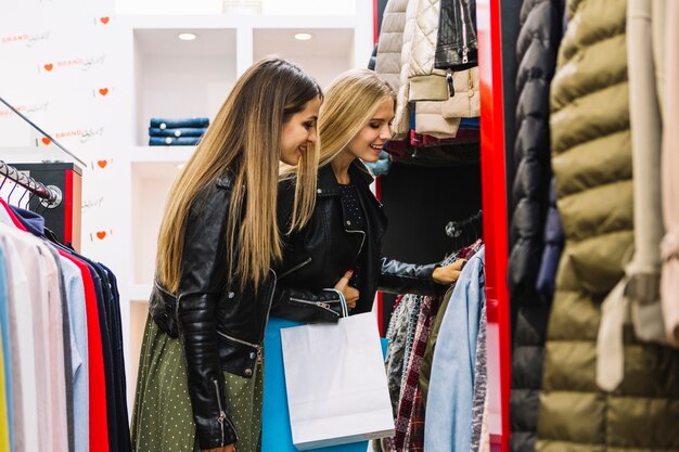 Dos mujeres jóvenes rubias mirando ropa en la tienda de compras