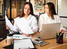 Foto gratuita dos mujeres jóvenes en el trabajo colaborando