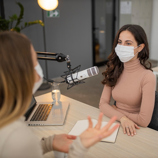 Dos mujeres con máscara médica conversando por radio