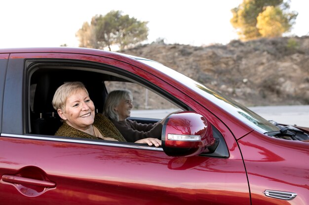 Dos mujeres mayores en el auto conduciendo y yendo a una aventura en la naturaleza