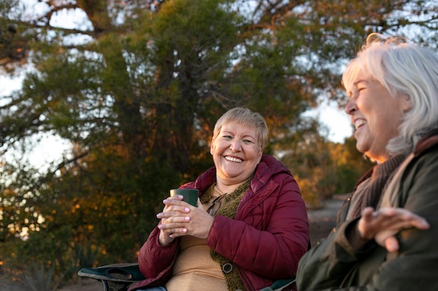 Dos mujeres mayores en una escapada a la naturaleza sentadas en sillas y disfrutando de su tiempo