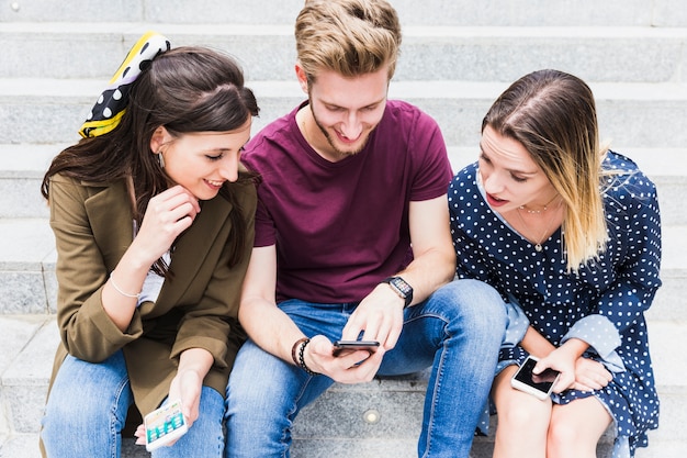 Dos mujeres mirando la pantalla del teléfono móvil del hombre