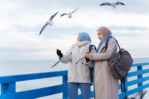 Foto gratuita dos mujeres musulmanas caminando por el par mientras viajan