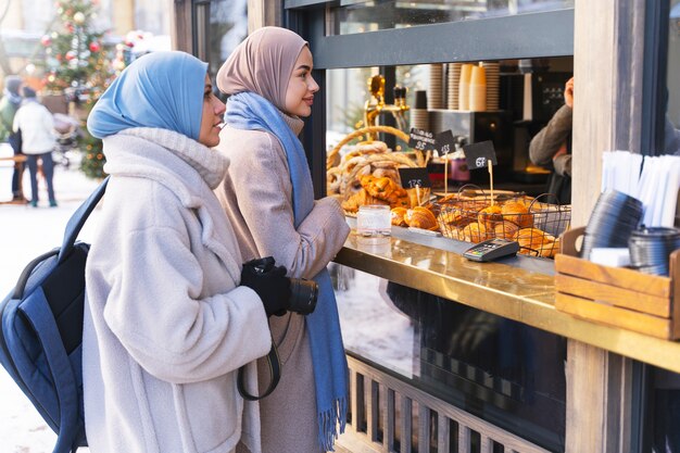 Dos mujeres musulmanas comprando comida en una pastelería mientras viajan