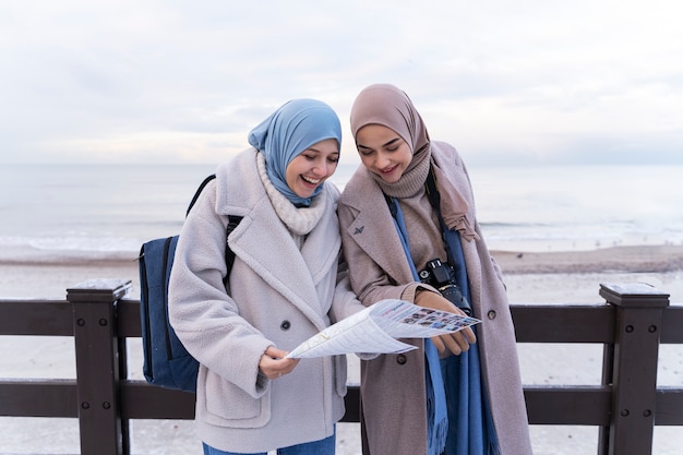 Dos mujeres musulmanas con hijabs consultando el mapa mientras viajan