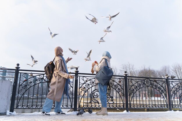 Dos mujeres musulmanas con hijabs mirando las palomas mientras viajan