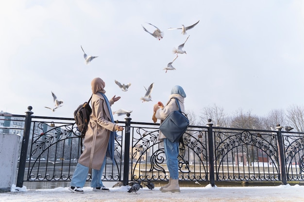 Dos mujeres musulmanas con hijabs mirando las palomas mientras viajan
